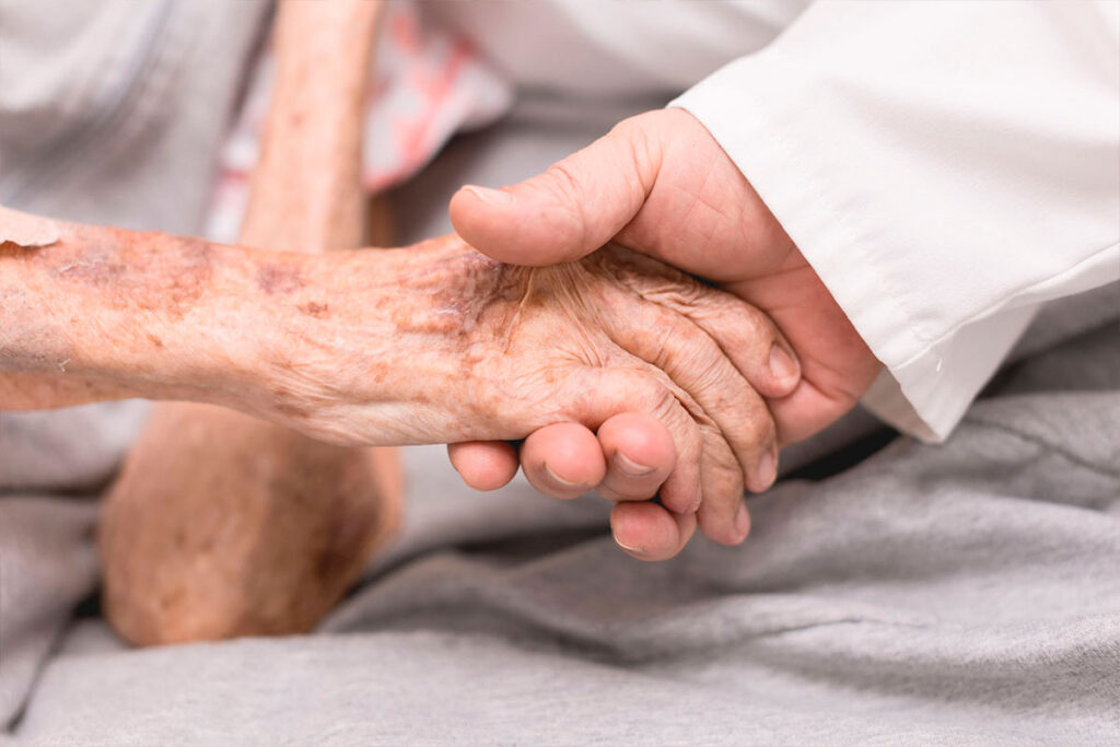 Profesional de la salud sostiene la mano de una persona mayor