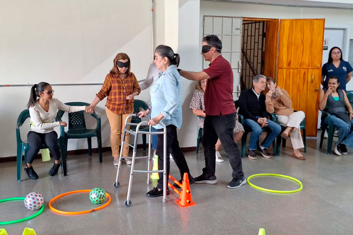 Adultos mayores realizan ejercicios con caminador y aros durante la terapia física