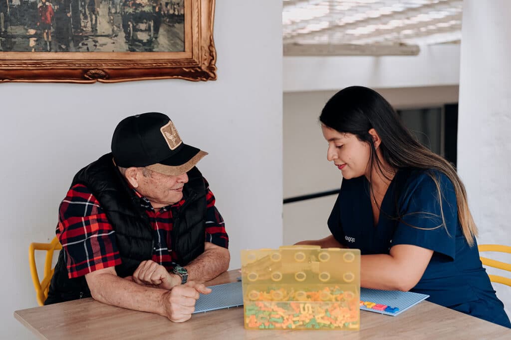 Profesional conversa con un adulto mayor durante una actividad