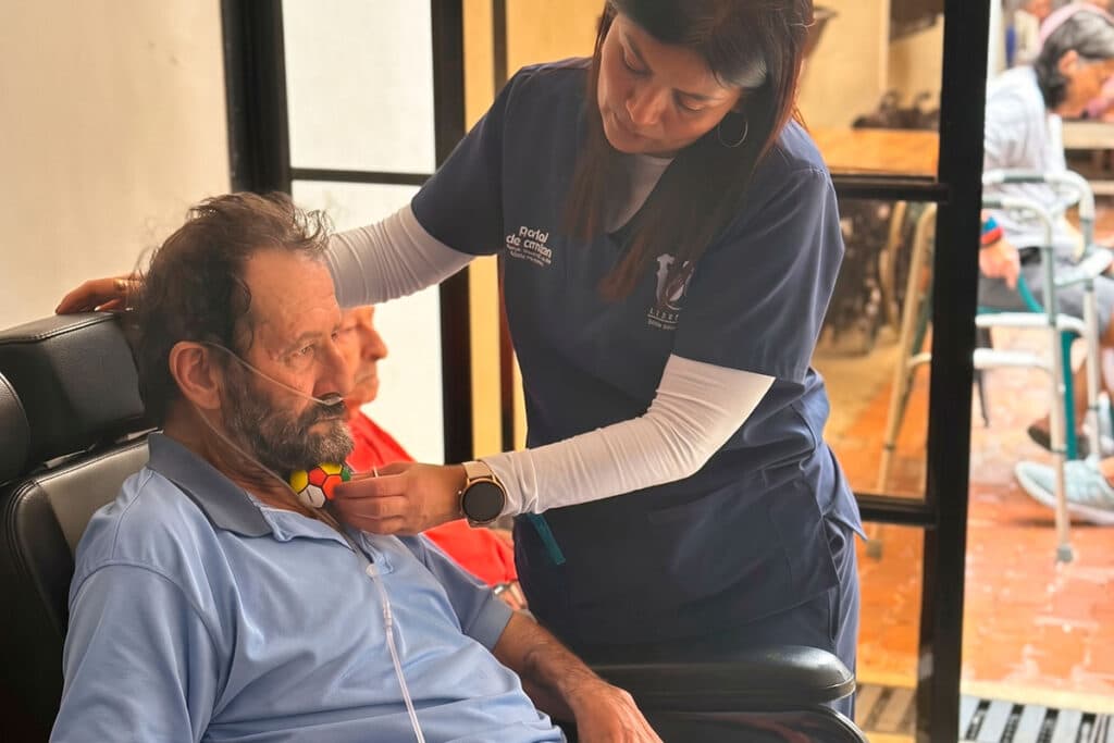 Fisioterapeuta realiza ejercicios de brazo con un adulto mayor sentado